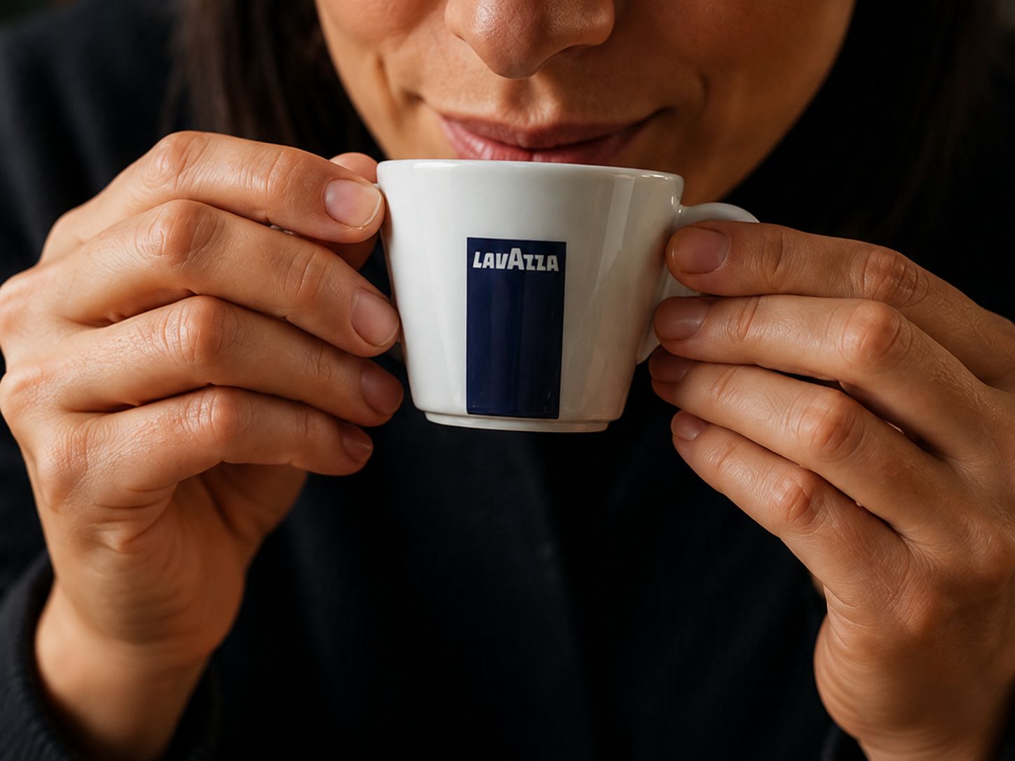 Žena drži šalicu Lavazza kave i ispija ju 